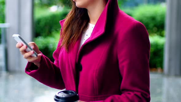 Businesswoman using mobile phone while having coffee