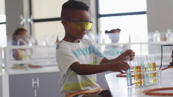 Video of happy african american boy wearing glasses during chemistry lesson