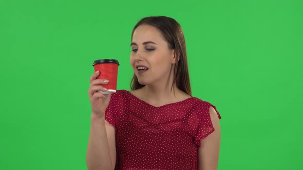 Portrait of Tender Girl in Red Dress Drinking Unpalatable Coffee and Is Disgusted. Green Screen