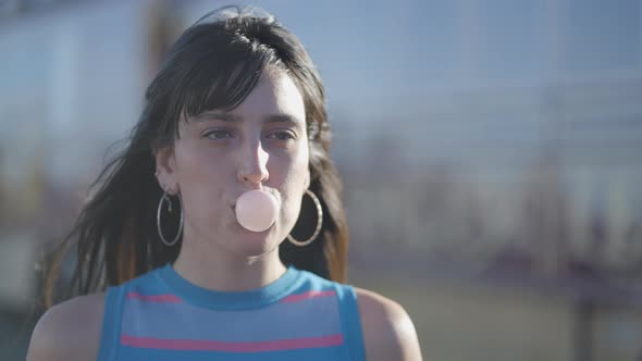 Close Frontal View of Darkhaired Girl Blowing Bubble with Chewing Gum