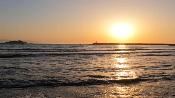 Slow motion shoot on sea waves on beach with lighthouse and island view at sunset alt