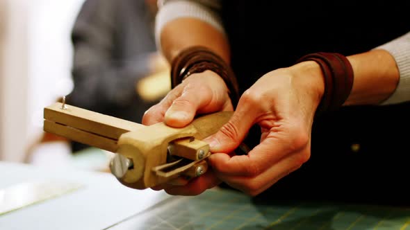 Mid-section of craftswoman preparing leather belt