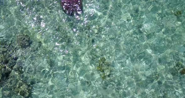 Wide overhead island view of a sandy white paradise beach and blue sea background in colourful 