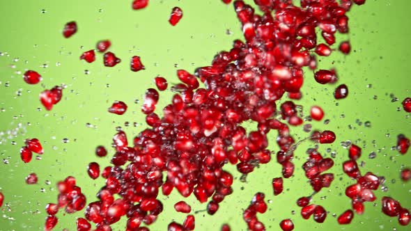 Super Slow Motion Shot of Fresh Pomegranate Seeds and Water Side Collision on Green at 1000Fps