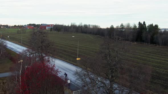 Man Skiing Down Wet Street In The Evening Near Ostersund, Sweden. 4K Drone.