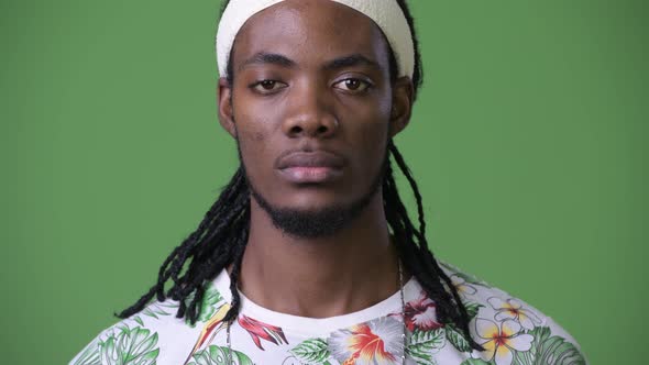 Young Handsome African Man with Dreadlocks Against Green Background