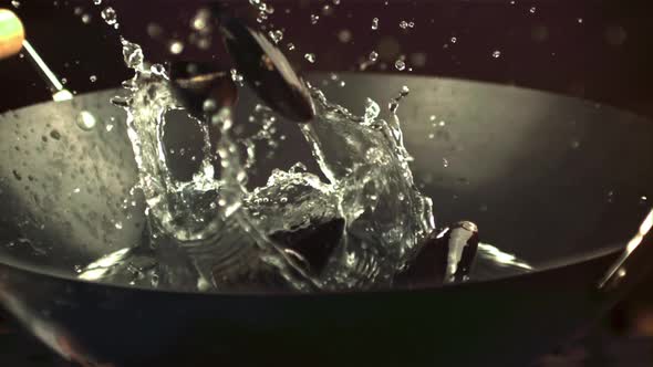 Super Slow Motion Mussels Fall Into a Pan with Water Spray