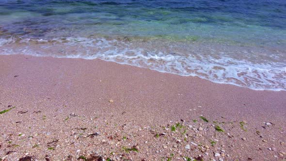 Sunny Beach with Blue Sea Water, Blue Sky and Rocks on the Horizon in a Summer Day. Middle Shot