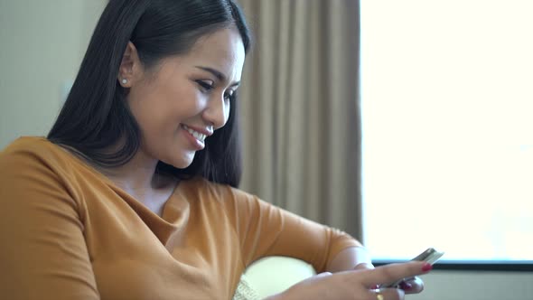 Relaxed young woman using smart phone sit on couch at home