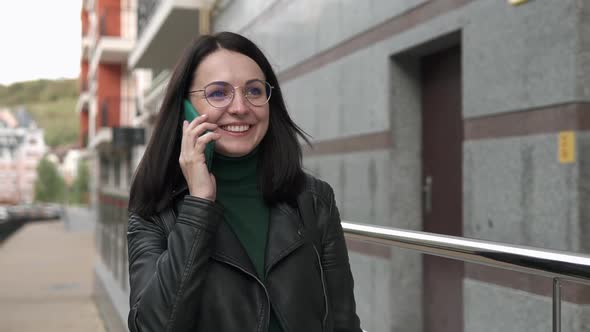 A beautiful European girl talking on the phone in a big city.