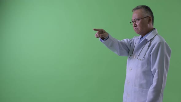 Profile View of Happy Mature Japanese Man Doctor Pointing Finger