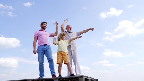 Family of Boy Child with Father and Old Man Point Fingers Holding Paper Planes Skyhigh Throwing