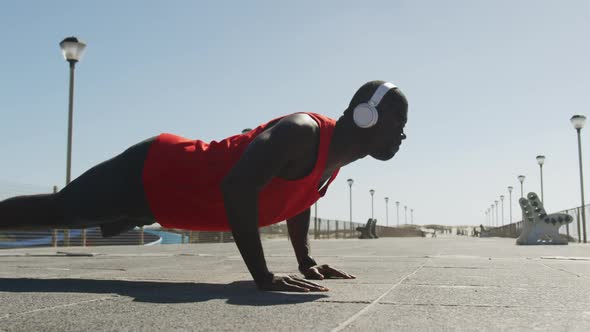 Focused african american man doing press ups, exercising outdoors by the seaside