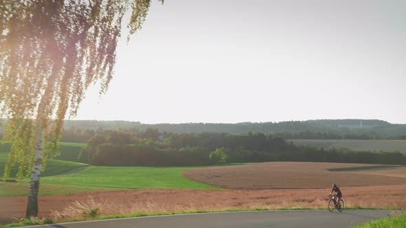 Woman riding bicycle at countryside at sunset. 