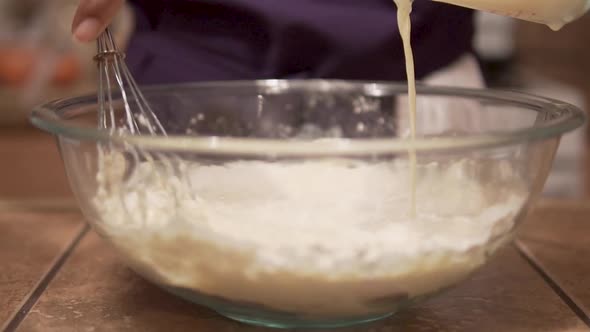 Slow Motion Close Up, pouring liquid and mixing batter in glass bowl