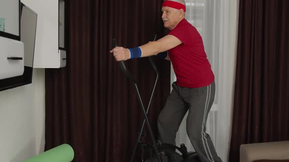 Active Healthy Senior Old Mature Man in Sportswear Using Orbitrek Training Cardio Workout at Home