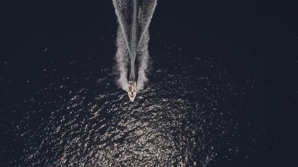 Aerial view of small speed boat with trailing wake on sea.