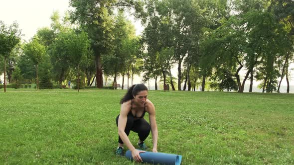 Young Woman Rolling Up Exercise Mat and Preparing Doing Yoga