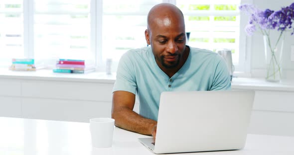 Man using laptop in kitchen 4k