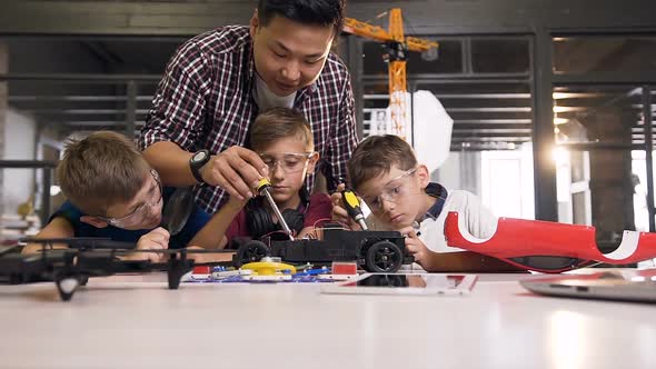 Asian Male Teacher is Helping and explaining young schoolchildren how using screwdriver fixing