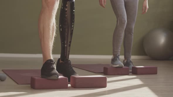 Man with Prosthetic Leg and Coach Exercising with Gym Blocks