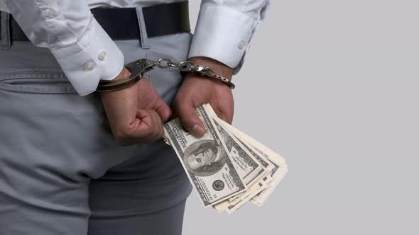 Darkskinned Businessman's Hands in Handcuffs Holding Money