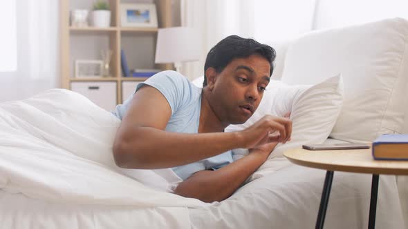 Indian Man Suddenly Awaking and Looking at Phone