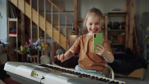 The Child Calls the Parents Via Video Link and Shows How She Plays the Synthesizer