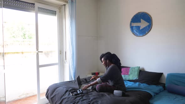 Young woman sitting on bed during video call