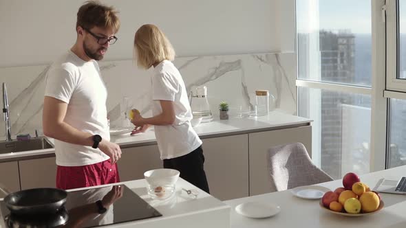 Beautiful Young Caucasian Man Preparing Breakfast for Two in Kitchen at Home and Mixing Eggs in Bowl