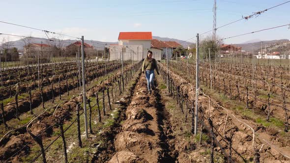 Young girl dressed casually walking on muddy areas amidst grape vineyard in beautiful suburbs. Podgo