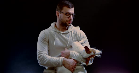 Cute Playful Dog Is Sitting on Laps of Male Owner in Studio