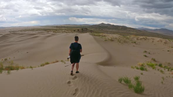 Following woman hiking on sand dune in the Utah desert