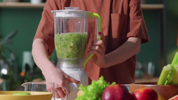 Woman Making Green Smoothie in Blender at Home