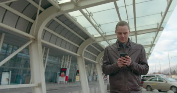 The Guy Is Typing the Message When He Passing the Airport and Hiding the Phone in the Pocket of His