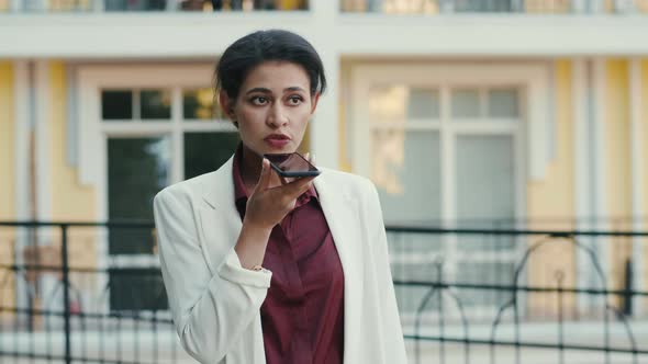 Serious Mixed Race Woman Discussing Project on Smartphone Outside