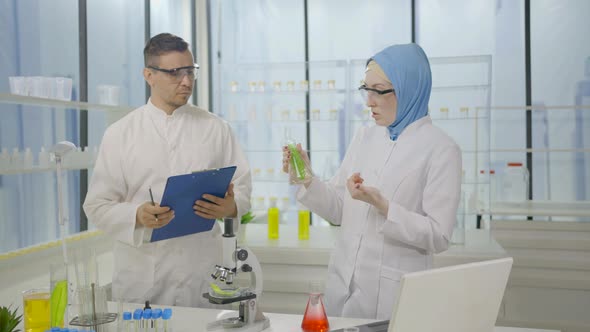 Two Muslim Scientists in Lab Coats in a Modern Laboratory are Talking