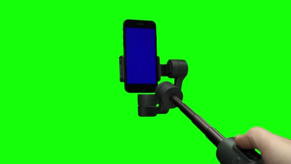 Filmmaker's Hand Lifting Up Steadicam with Blue Screen on Smartphone.