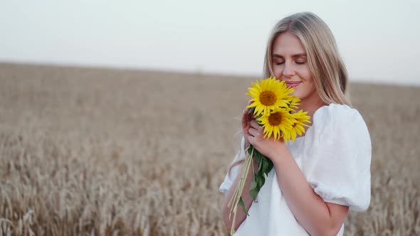 Woman with Sunflowers in a Dress in a Summer Wheat Field