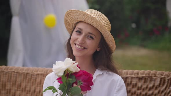 Front View Zoom in of Beautiful Slim Caucasian Young Woman Smelling Bouquet of Roses Smiling Looking