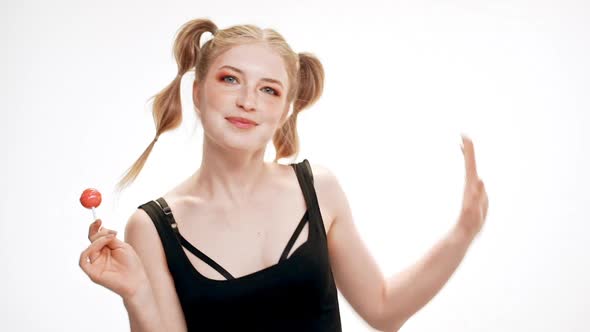 Young Beautiful Girl Dancing Smiling Holding Chupa Chups Singing Over White Background