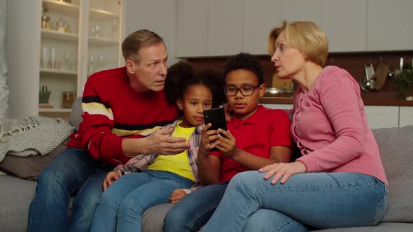 Relaxed Multicultural Grandchildren with Grandparents Networking on Cellphone