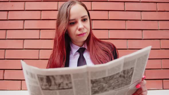 Young Woman Reading Newspaper on Street