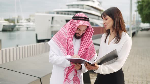 Arab Man Signing Contract with Businesswoman