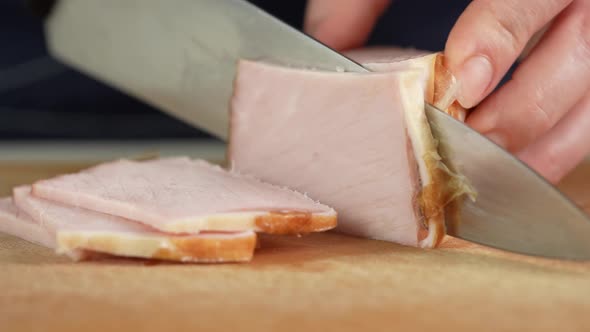 Slicing Traditional Ham Into Pieces on a Cutting Board with a Knife