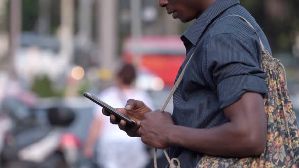 Smiling black american man in the street looking on smartphone