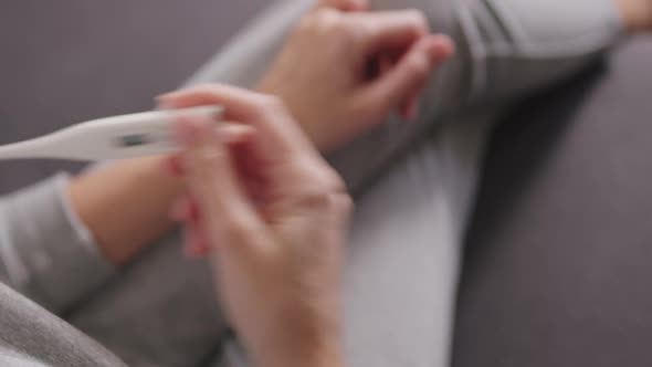 Woman Measuring Her High Body Temperature Using an Electronic Thermometer