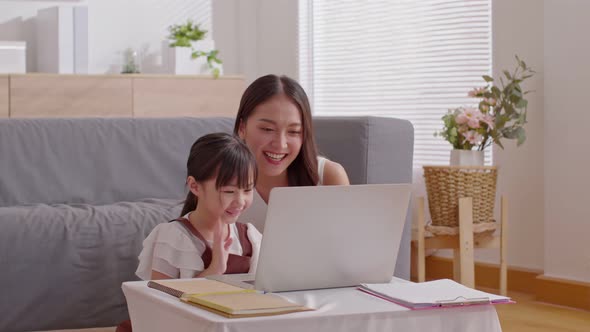 Asian young mother and her daughter have video call conference with family having fun together