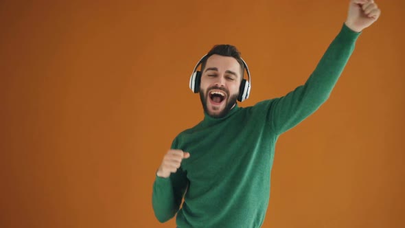 Slow Motion of Bearded Young Man Listening To Music Through Headphones and Dancing Having Fun