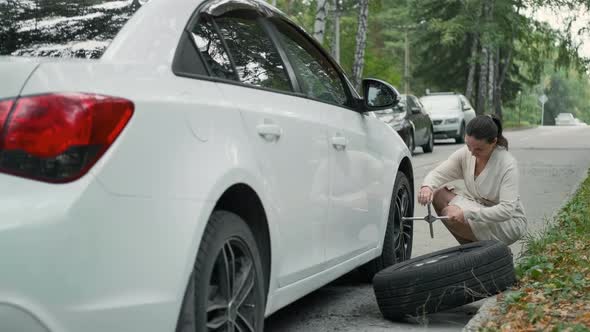 Female with Heels Trying to Change Tire on a Road